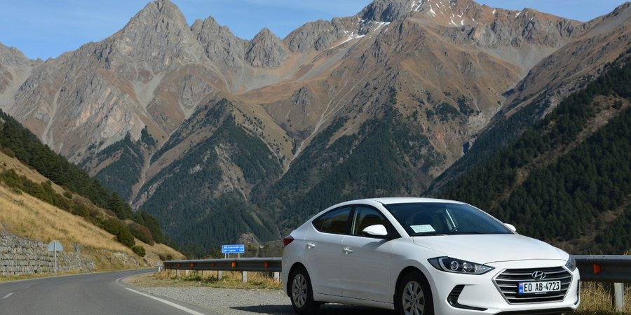 Rental car parked against Caucasus mountain backdrop in Georgia