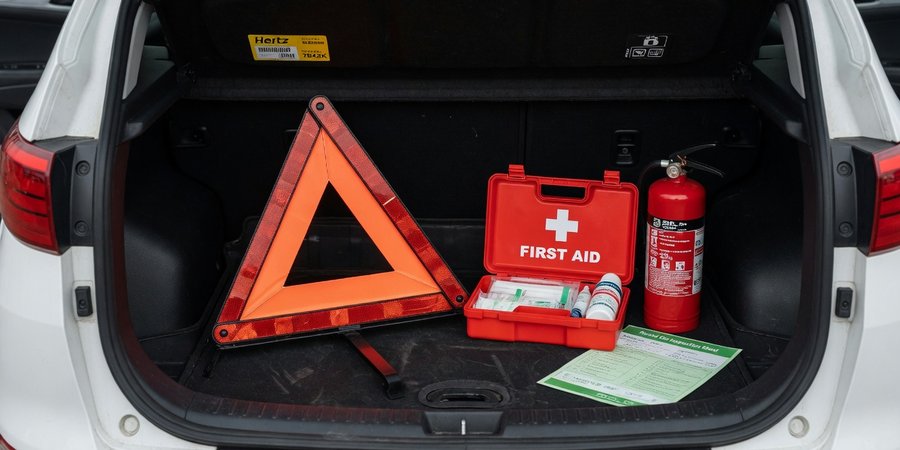 Open boot of a rental car with triangle, first-aid kit and extinguisher
