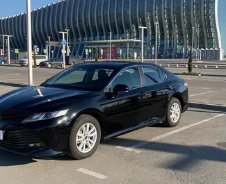 Frontvisning av en leiebil Toyota Camry på Simferopol lufthavn, Krim ✓ Bil #1825. ✓ Automatisk TM ✓ 0 anmeldelser.