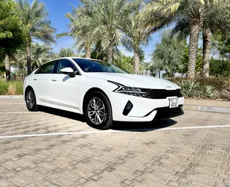 Vista frontal de un Kia K5 de alquiler en el aeropuerto Al Maktoum de Dubai, EAU ✓ Coche n.º 8319. ✓ Automático TM ✓ 0 opiniones.