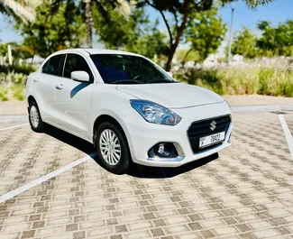 Predný pohľad na prenajaté auto Suzuki Dzire v na letisku Al Maktúm v Dubaji, SAE ✓ Auto č. 9131. ✓ Prevodovka Automatické TM ✓ Hodnotenia 0.