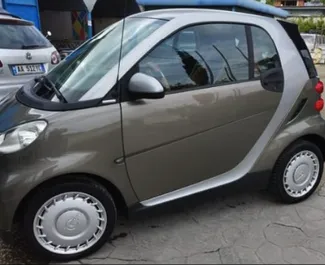 Vista frontal de um aluguel Smart Fortwo no aeroporto de Tirana, Albânia ✓ Carro #10011. ✓ Transmissão Automático TM ✓ 0 avaliações.