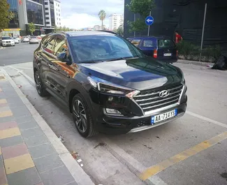 Vista frontal de um aluguel Hyundai Tucson no aeroporto de Tirana, Albânia ✓ Carro #11499. ✓ Transmissão Automático TM ✓ 0 avaliações.