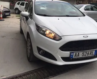 Vista frontal de um aluguel Ford Fiesta no aeroporto de Tirana, Albânia ✓ Carro #11488. ✓ Transmissão Manual TM ✓ 0 avaliações.