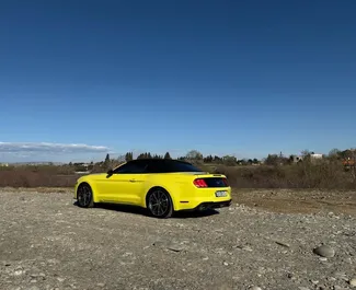 Vista frontal de um aluguel Ford Mustang Cabrio em Tbilisi, Geórgia ✓ Carro #12494. ✓ Transmissão Automático TM ✓ 0 avaliações.