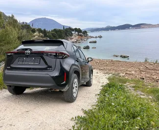 Front view of a rental Toyota Yaris Cross at Podgorica Airport, Montenegro ✓ Car #16211. ✓ Automatic TM ✓ 0 reviews.